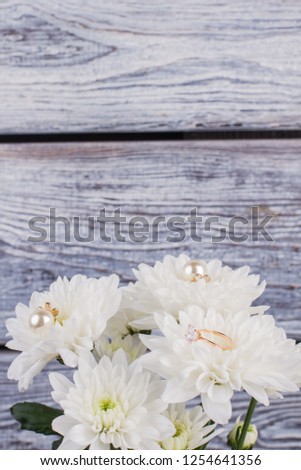 White chrysanthemum flowers on wooden background. Marriage proposal with bouquet of flowers and golden ring. Vintage effect.