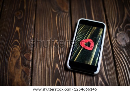 Smartphone on wooden background and a heart symbol on the screen