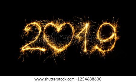 Happy New Year 2019. Number 2019 written sparkling sparklers isolated on black background for design. Beautiful Glowing overlay template for holiday greeting card. Royalty-Free Stock Photo #1254688600