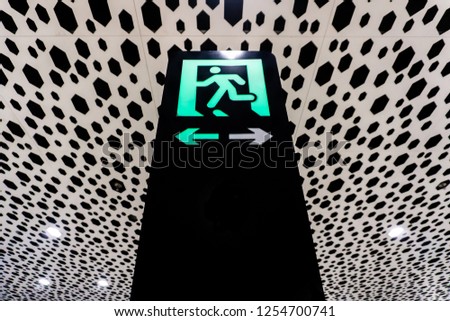 Airport Green Colored Emergency Exit on Black Pillar with Arrows