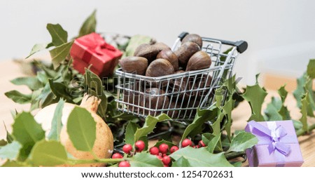 Fall and winter seasonal background, copy space image with laurel leaves and a shopping trolley full of chestnuts
