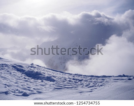 Fresh snow in the Alps and huge cloud concealing high peak in background