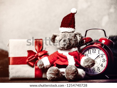 Christmas gift with bowknot and retro alarm clock with teddy bear on grey background
