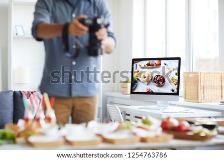 Mid section portrait of unrecognizable photographer taking picture of table with food, focus on computer screen in background, copy space