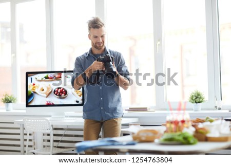 Portrait of successful photographer taking pictures of table with food while working in photo studio, copy space