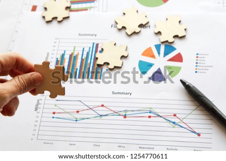 Hand shows jigsaw over sale chart with black pen pointing the chart. business concept Royalty-Free Stock Photo #1254770611