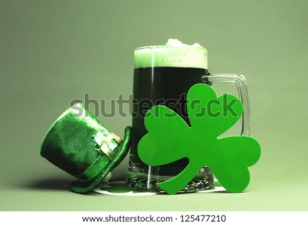 St Patrick's Day green beer with shamrock and Leprechaun hat against green background.