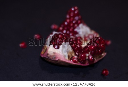 Pomegranate or garnet fruit on the dark surface, close-up with seeds