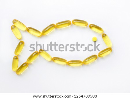 Capsules of fish oil laid out in the form of fish. Fish oil capsules in yellow on a white background. Health care, nutritional supplements for athletes.