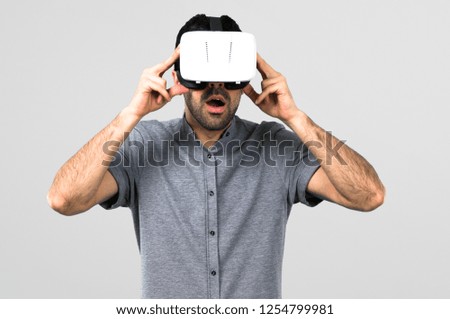 Handsome man using VR glasses on grey background