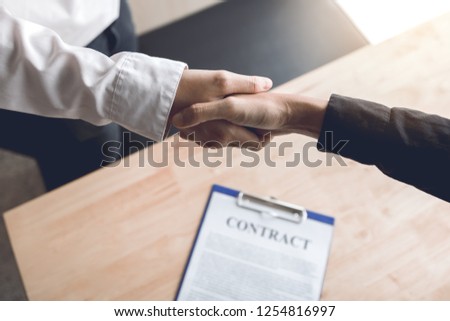 Confident partnerships people shaking hands with making a contract in the office.