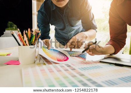 Graphic designer working at his desk and is choosing colors together.