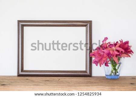 Brown wooden frame with pink orchid flowers on table