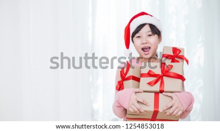 Portrait of little beautiful asian Japanese teenage girl wearing red hat holding big gift box with copy space, christmas boxing day open present concept panoramic banner