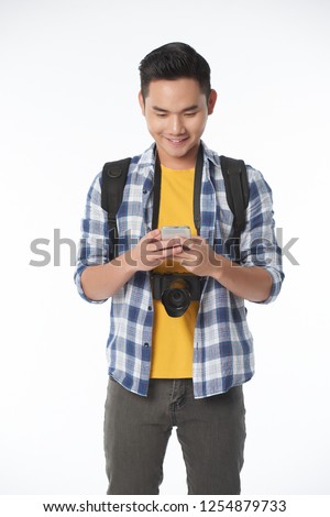 Handsome young smiling Asian traveler using map application on his smartphone