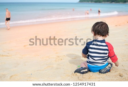 Baby sit on the beach playing sand