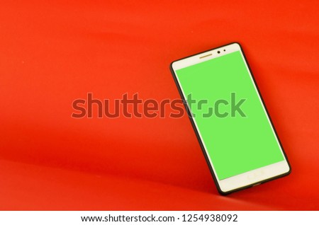 blurred A green mobile phone laying on a red background 