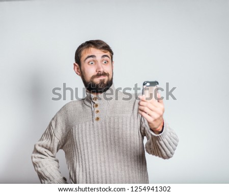 handsome bearded man makes fun selfie photos on a smartphone, close up on background