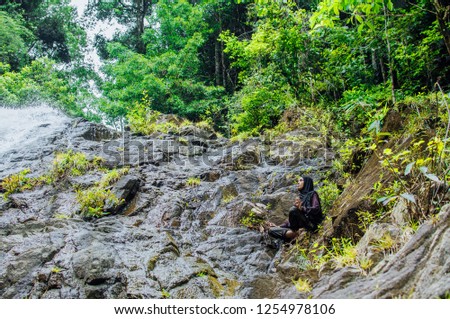 Muslim woman in hijab exercising healthy lifestyle yoga exercise over the waterfall background. Meditation relaxation concept.