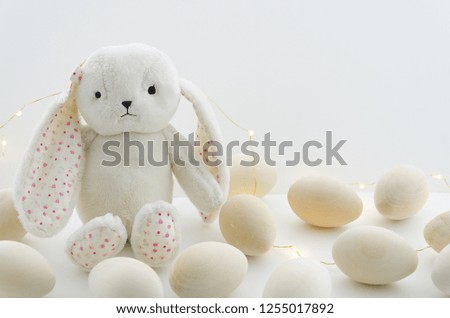 Cute white rabbit bunny toy and wooden decorative eggs. Bright Easter mockup background with copy spaces. Happy Easter eggs concept