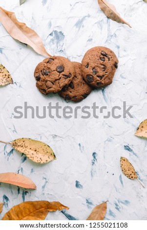 Autumn still life. Cookies and autumn leaves on white cement background.