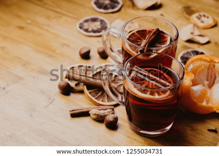 Mulled wine in mugs with scarf on wooden table
