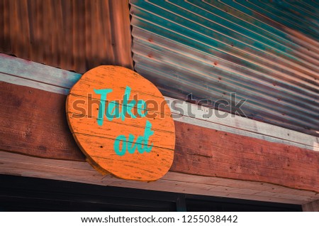 Wooden take out signage above the counter of a fast food store