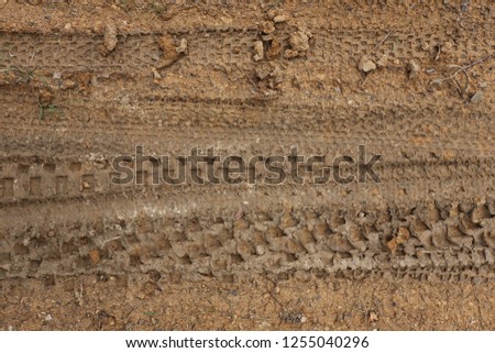 Close up outdoor view from above of tire tracks on a sandy ground. Abstract picture of pattern of bicycle marks on a wet soil. Textured surface with group of lines and long shapes.