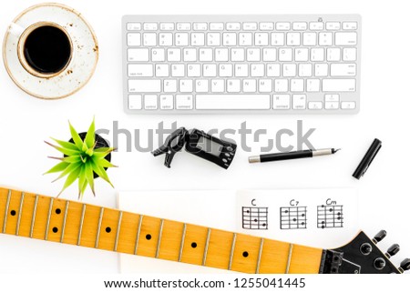 Desk of musician for songwriter work with coffee, keyboard, guitar and notes marble background top view