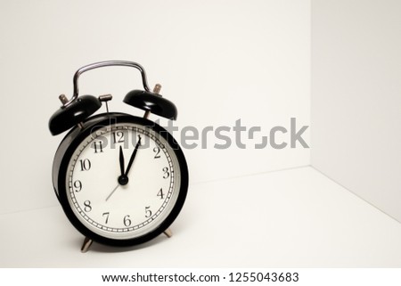 Close up view of black alarm clock with white dial and on a white background