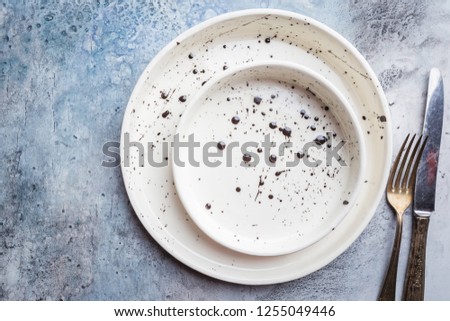 Two handmade empty white plates on blue background. Top view with copy space