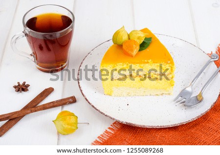 Piece of mango mousse cake on plate, white wooden table. Studio Photo
