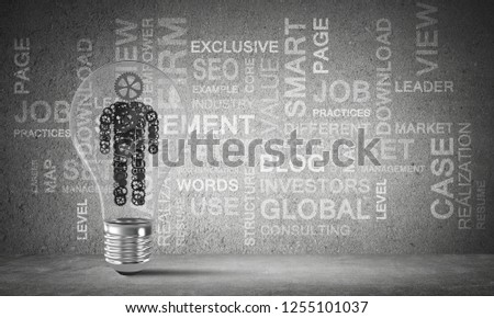 Glass lightbulb with human from gears inside against business related terms on grey wall on background. 3D rendering.