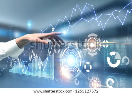 Hand of businesswoman in white shirt working with graph interface and business infographics with hud over blurred background. Toned image double exposure