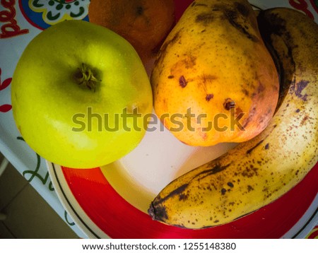 A close up photo of four basic and tasty fruits that pediatricians recommend as first solid food for six month babies. The fruits in the picture are an apple, a pear, a banana, and an orange.