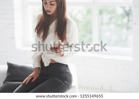 Close up photo of beautiful young girl in black jeans sitting and holding glass with whiskey.
