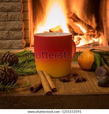 Merry Christmas near cozy fireplace, with mug of hot drink, cinnamon sticks, cones, nuts, tangarine over old brown desk ,in country house, vertical.