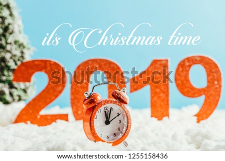 big red 2019 numbers with vintage alarm clock standing on snow on blue background with "it is christmas time" lettering