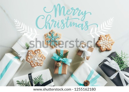 flat lay with christmas gift boxes and snowflake cookies on marble background with "merry christmas" lettering