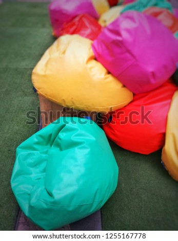 Blur picture of colorful bean bag seat on artificial grass.Green yellow Purple Proton  and red color tone.