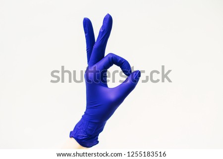 Female hand in blue medical glove on white background, everything is good symbol