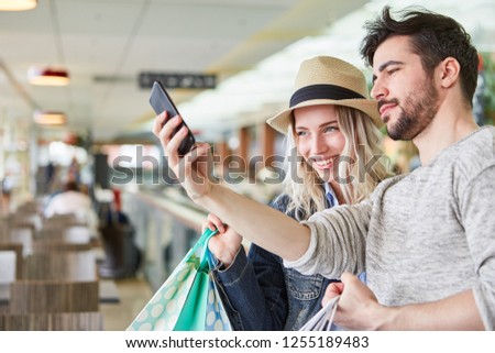 Young couple photographing themselves with their smartphone while shopping