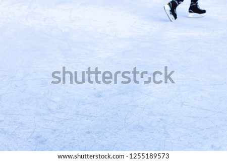 Legs of an ice skater in old vintage skates. Ice skratched background.