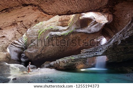 Young woman looking at hidden waterfall into Canyon.