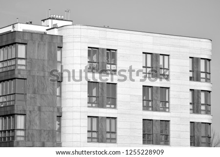 Fragment of a facade of a building with windows and balconies. Modern home with many flats. Black and white.