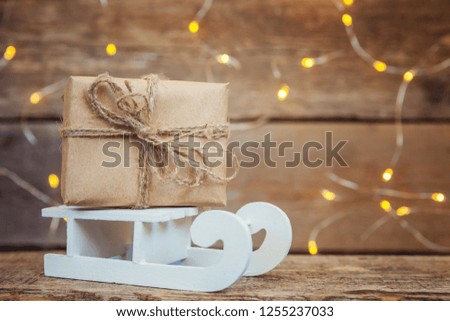 Christmas New Year composition winter objects garland lights gift box and sled on old shabby rustic wooden background. Xmas holiday december decoration copy space. Time for celebration