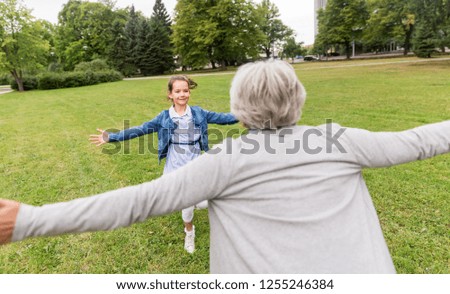 family, leisure and people concept - happy grandmother and granddaughter playing game or meeting at summer park