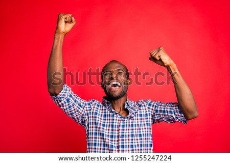Portrait of nice handsome attractive cheerful glad positive guy wearing checked shirt showing breakthrough gesture holding fists raising hands up isolated over bright vivid shine red background