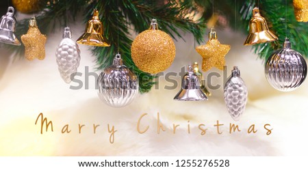 Shiny gold and silver christmas balls, stars and bells on white with pine tree for new year with marry christmas text.