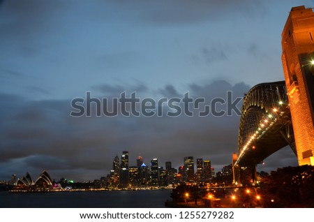 Colorful light reflection at Sydney Harbour Bridge, viewed from Milsons Point, Australia. The Iconic Landscape of illuminated Sydney city Harbour Bridge at night with cloudy sky.